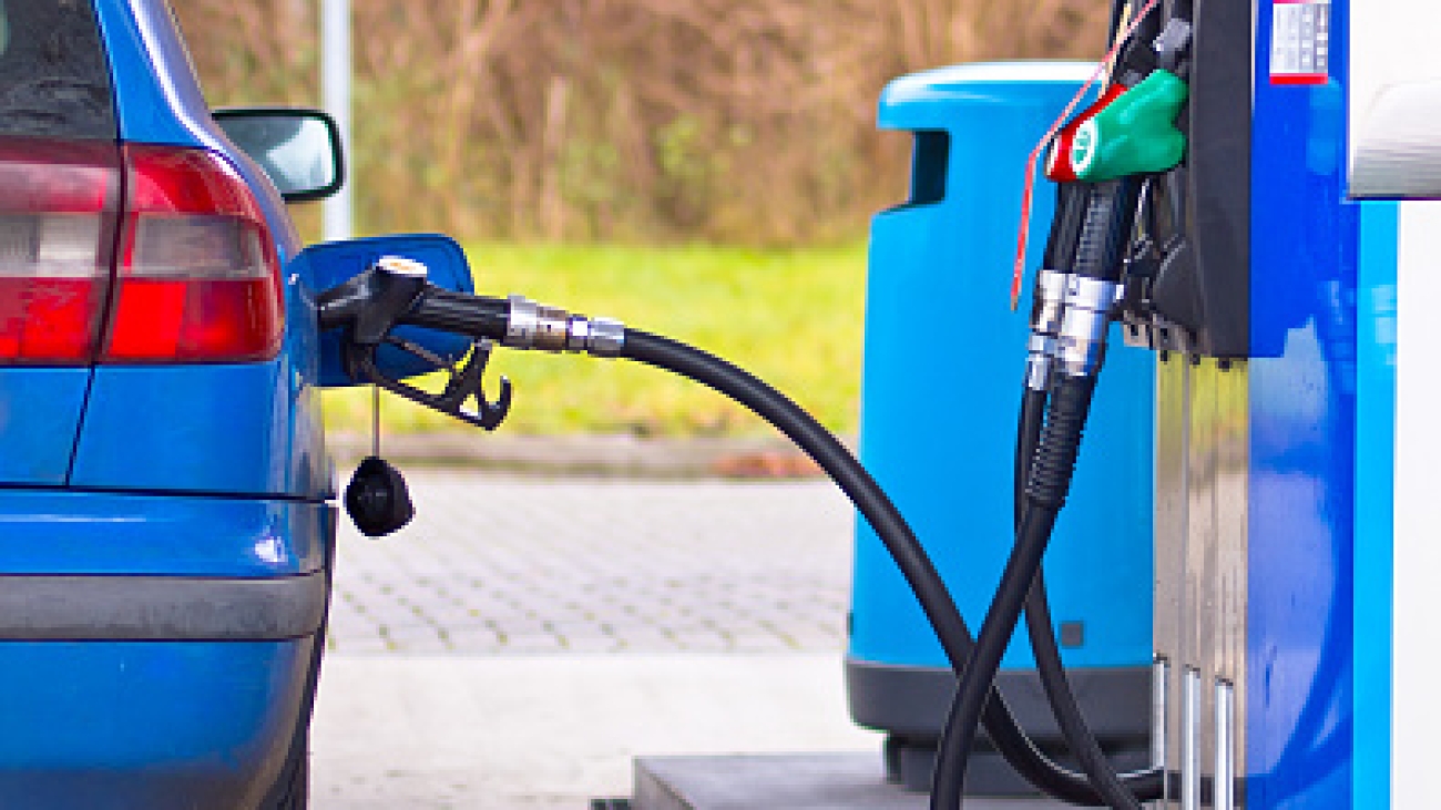 Blue car at gas station being filled with fuel against inflated prices