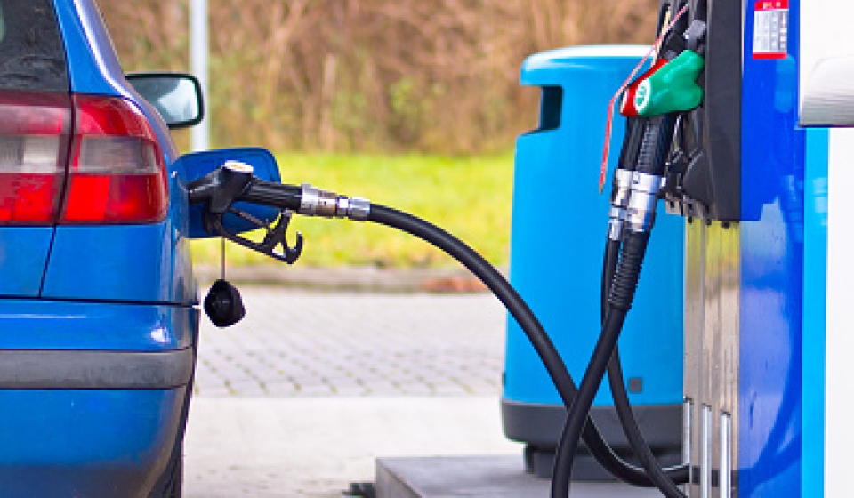 Blue car at gas station being filled with fuel against inflated prices